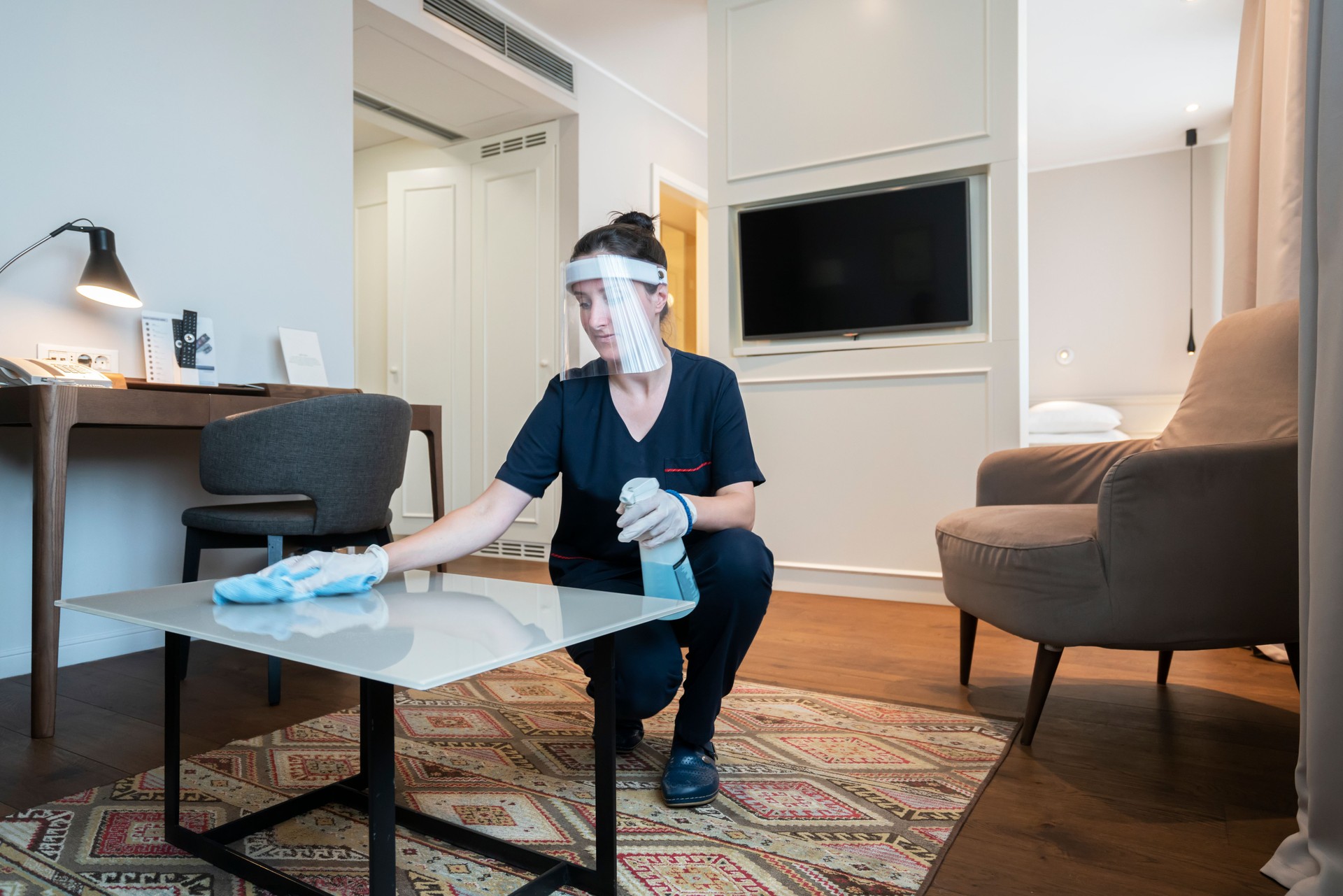 Maid cleaning hotel room, wearing a face mask while working at a hotel